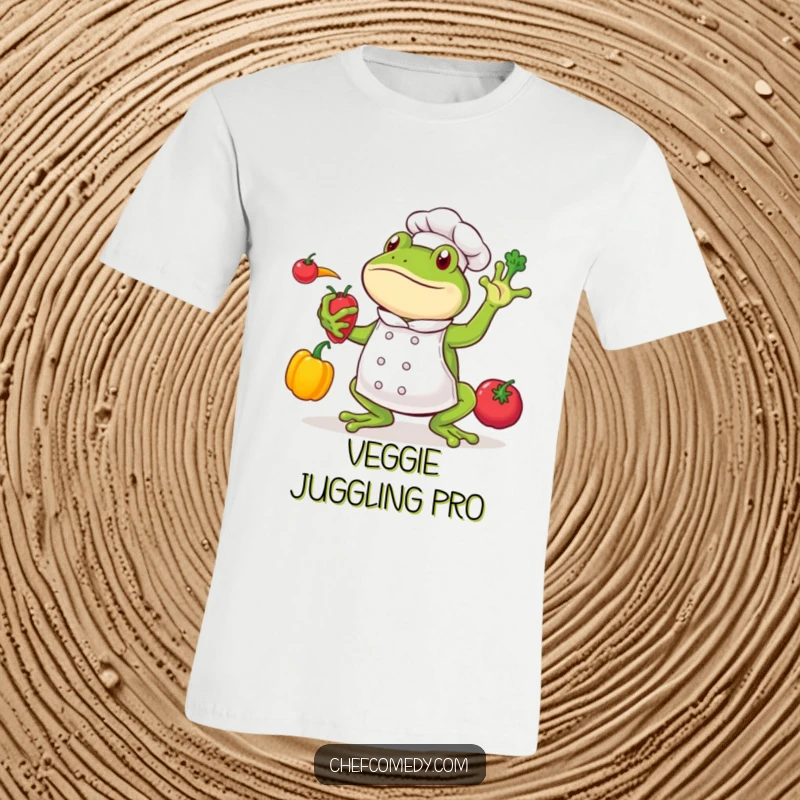 Funny frog chef character balancing three colorful vegetables in the air, smiling widely, printed on a t-shirt.